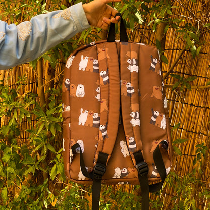 Brown backpack with bear pattern held by a person against a natural background